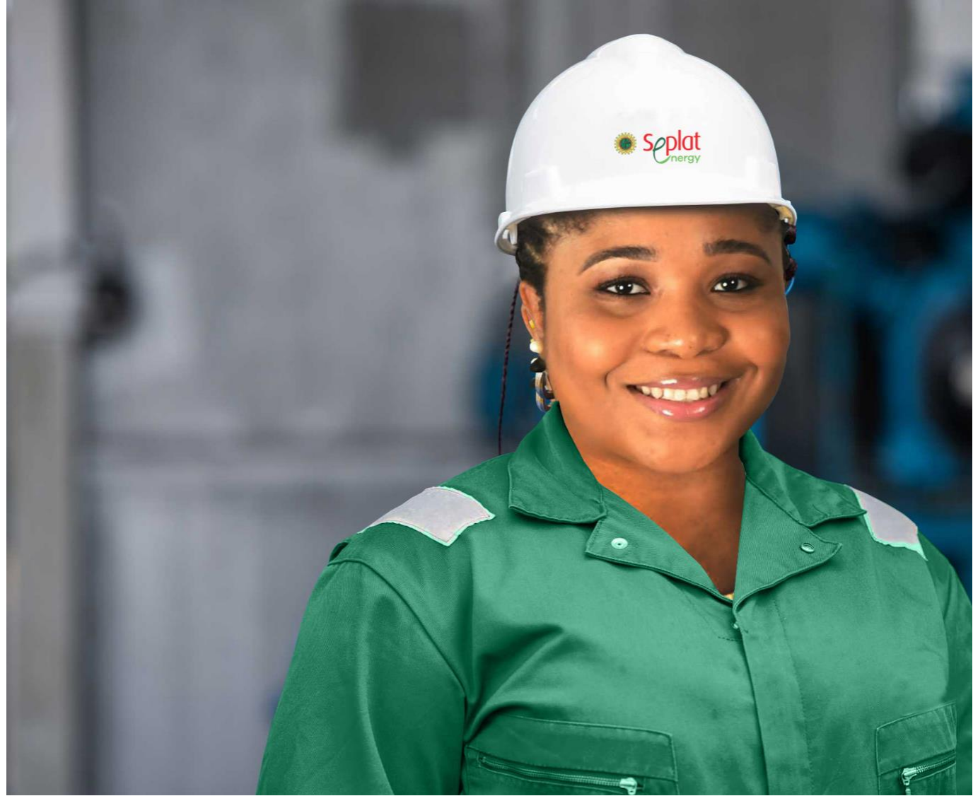 Woman in a white hard hat and green Seplat Energy coveralls smiling near industrial pipework.