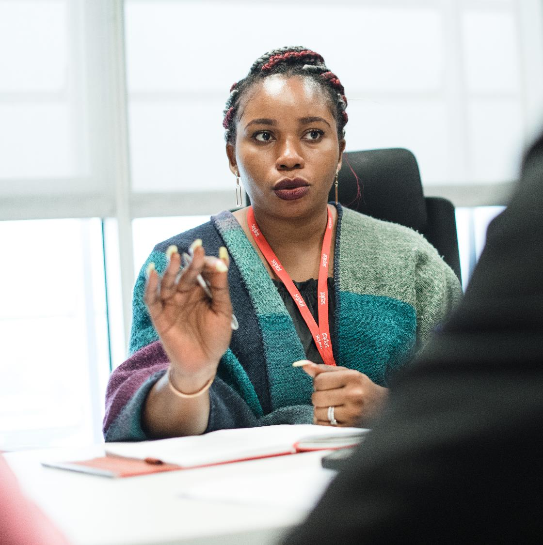 Woman wearing a Seplat lanyard gesturing while speaking in a meeting.