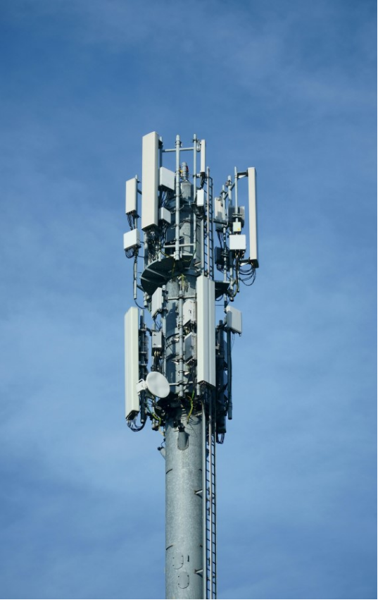 Telecommunications network tower against a clear sky.