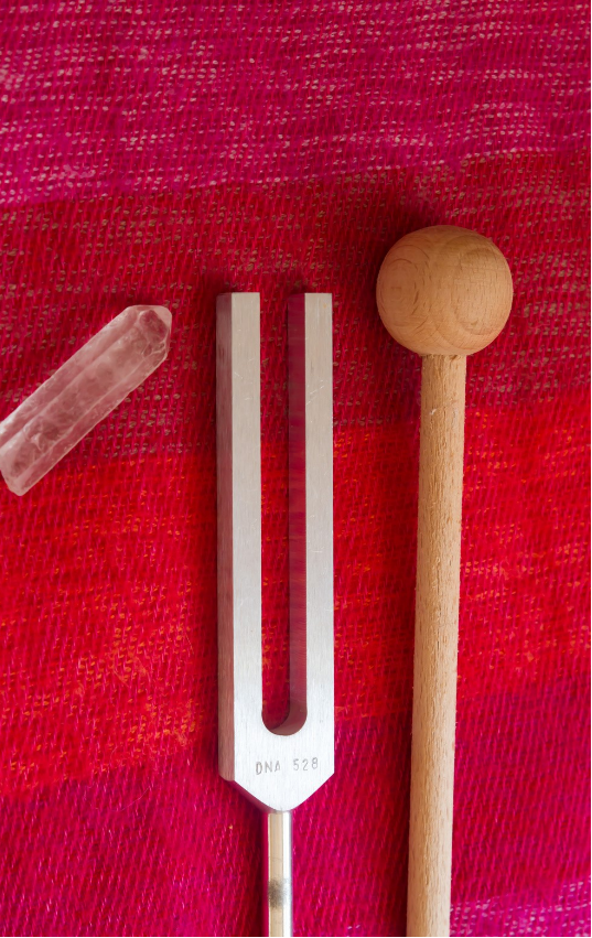 Tuning fork and crystal resting on red fabric, symbolizing resonance.